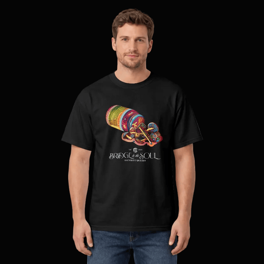 A man wearing a black short-sleeve t-shirt with a colorful graphic of a mushrooms spilling out of a pill vial and the text 'BRIDGE TO THE SOUL-NATURES REMEDY' on the front, set against a black background